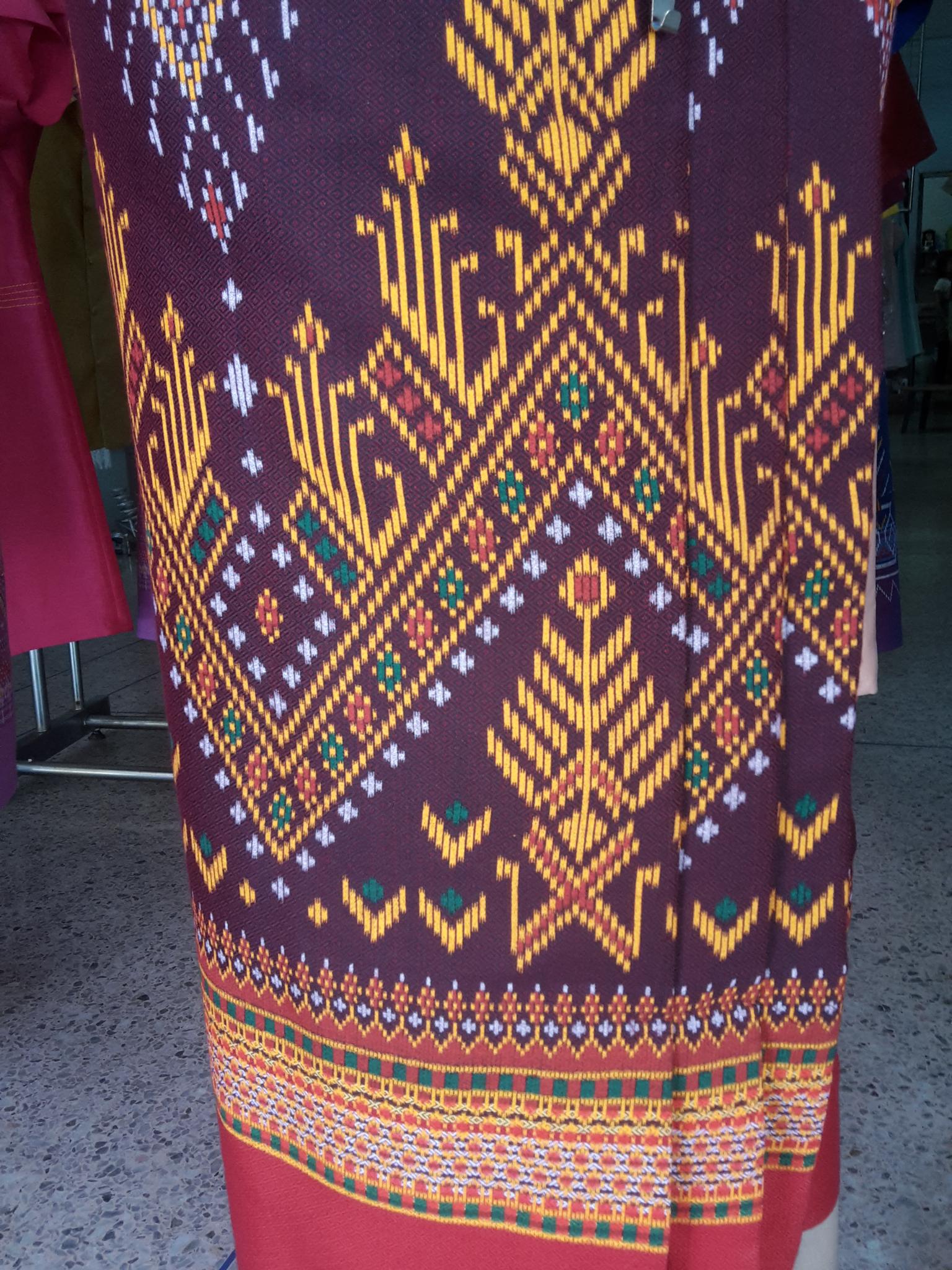 ผ้าซิ่นสำเร็จรูปผ้าซิ่นผ้าฝ้าย แบบป้ายแต่งจีบกระดุมปั้มลายพนมอัปศราฉัตร ผ้าซิ่นตัดสำเร็จพื้นม่วงตีนแดง